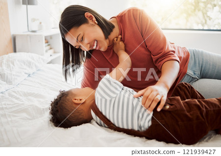 Happy, loving family with a mother and son being playful and bonding on a bed at home. Smiling parent playing with her child, laughing and enjoying motherhood. Single parent embracing her son 121939427