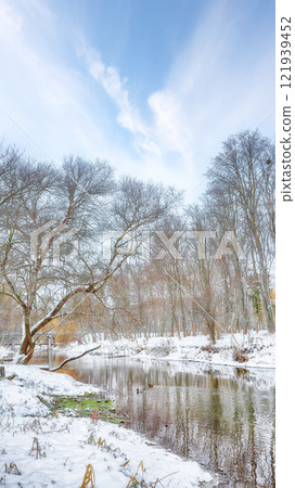 Excellent landscape in city park with snowy trees and beautiful frozen river. Excellent landscape in city park with snowy trees and beautiful frozen river. 121939452