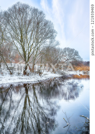 Excellent landscape in city park with snowy trees and beautiful frozen river. Excellent landscape in city park with snowy trees and beautiful frozen river. 121939469