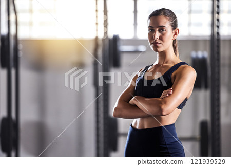 Fit, slim and serious woman with arms crossed, feeling confident about her body and health while standing in gym. Portrait of a sporty and determined woman ready to exercise to stay in healthy shape Fit, slim and serious woman with arms crossed, feeling confident about her body and health while standing in gym. Portrait of a sporty and determined woman ready to exercise to stay in healthy shape 121939529