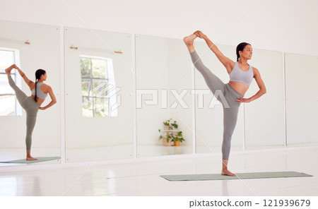 Yoga, fitness and wellness woman doing one leg up pose in a wellness studio with big mirror and copy space. Flexible, athletic and fit woman on an exercise mat while exercising for health and balance 121939679