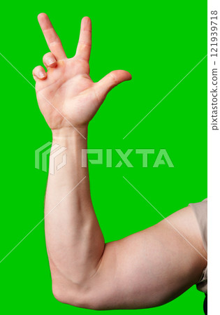 A hand gesturing three fingers with a green background 121939718