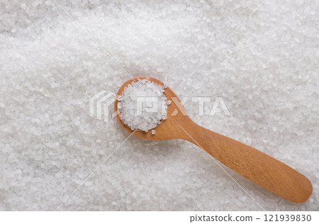 Coarse table salt in a wooden spoon background. Top view 121939830