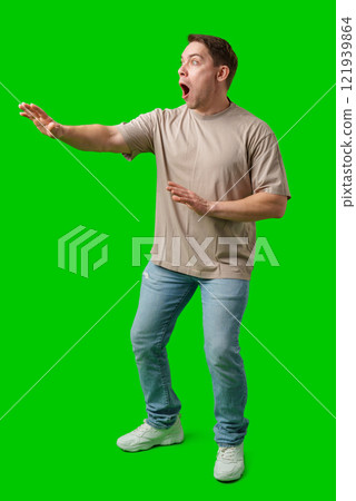 Man expressing fear while standing against a bright green background 121939864