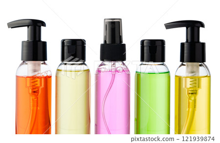 Various bottles with colored liquids and pumps arranged on white background 121939874