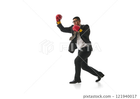 In mid-motion, man confidently punches air with his gloves, exuding sense of victory and resilience against white studio background. 121940017
