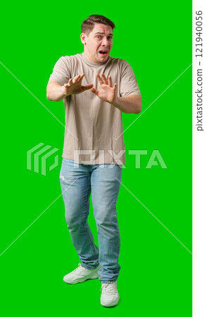 Man expressing fear while standing against a bright green background Man expressing fear while standing against a bright green background 121940056