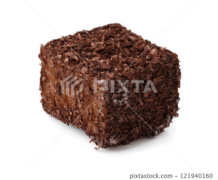 Chocolate square coated with coconut flakes sits on a white surface ready to be enjoyed as a sweet treat or dessert 121940160