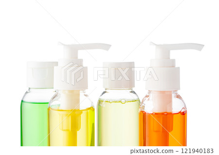Various bottles with colored liquids and pumps arranged on white background 121940183