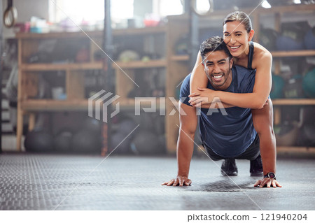 Fitness couple having fun while man does push ups and exercise together at the gym. Healthy, fit and athletic friends playing and silly while enjoying training session with teamwork at a health club 121940204