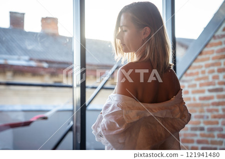 Woman relax in hotel room and standing near window. window reflection Woman relax in hotel room and standing near window. window reflection 121941480