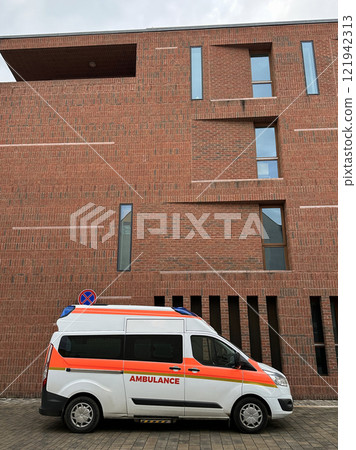 Ambulance next to a large brick walled building Ambulance next to a large brick walled building 121942313