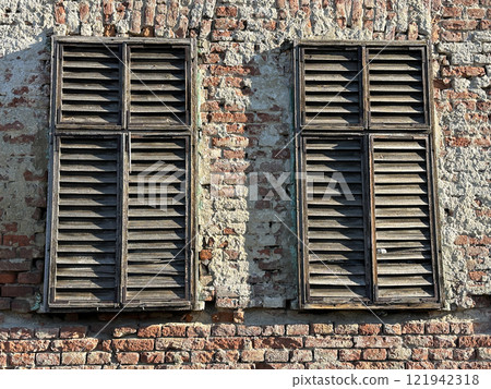Wooden shutters on the brick wall of a house 121942318