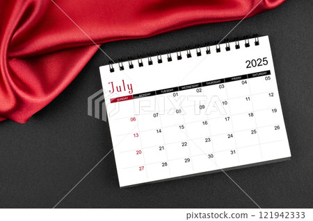 July 2025 Monthly desk calendar with red silk on black leather background. July 2025 Monthly desk calendar with red silk on black leather background. 121942333