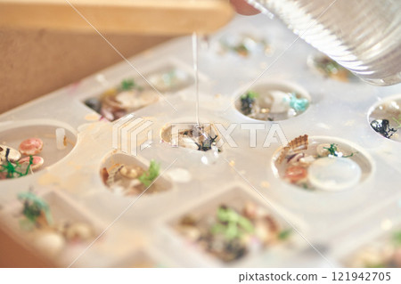 Handcrafted epoxy resin jewelry mold with shells and flowers in artistic process 121942705