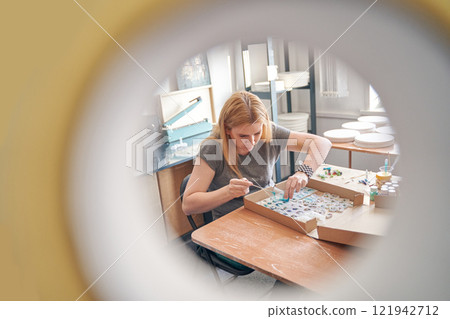 Caucasian female adult focused on creative crafting project in art studio Caucasian female adult focused on creative crafting project in art studio 121942712