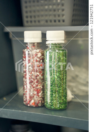 Colorful bead containers with red and green beads in clear plastic bottles Colorful bead containers with red and green beads in clear plastic bottles 121942751