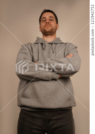 Male in casual clothes. Crossed hands. Front view. Handsome guy. Neutral background. Young man standing in front of camera. Man looking at camera. Male in casual clothes. Crossed hands. Front view. Handsome guy. Neutral background. Young man standing in front of camera. Man looking at camera. 121942752