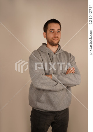 Male looking at camera. Guy in casual clothes. Crossed hands. Front view. Handsome man. Neutral background. Young man standing in front of camera. Male looking at camera. Guy in casual clothes. Crossed hands. Front view. Handsome man. Neutral background. Young man standing in front of camera. 121942754