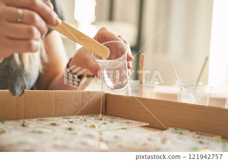 Female adult crafting with resin in creative workshop setting 121942757