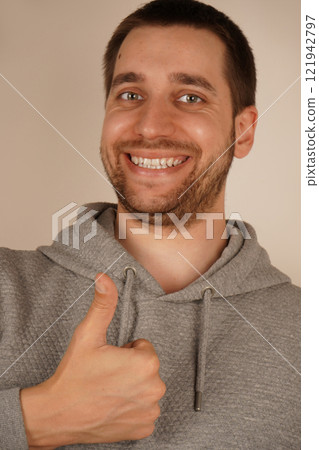 Young handsome man with beard over isolated gray background giving a thumbs up gesture. 121942797