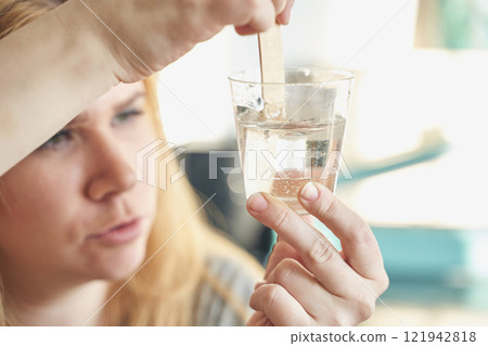 Caucasian young female examining clear liquid in a glass cup with wooden Caucasian young female examining clear liquid in a glass cup with wooden 121942818