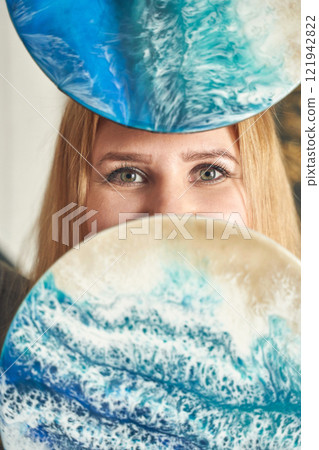 Caucasian female artist with blue resin art disks displaying ocean inspired Caucasian female artist with blue resin art disks displaying ocean inspired 121942822
