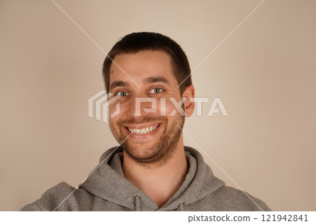 The guy has a small beard and a short haircut. The smile conveys a positive and good mood. The face of a man smiling broadly in positive emotions. The guy has a small beard and a short haircut. The smile conveys a positive and good mood. The face of a man smiling broadly in positive emotions. 121942841