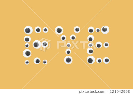 Googly eyes forming the word eye on a yellow background 121942998