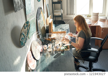Caucasian female adult artist creating unique ceramic designs in a bright studio Caucasian female adult artist creating unique ceramic designs in a bright studio 121943027