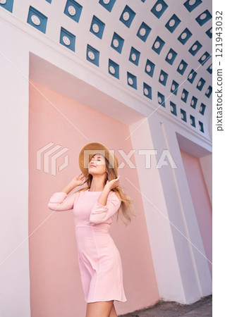 Young caucasian female in pink dress and straw hat under artistic ceiling 121943032