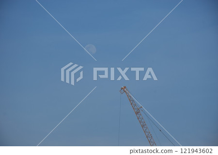 heavy crane on roof top of under construction building with moon in evening 121943602