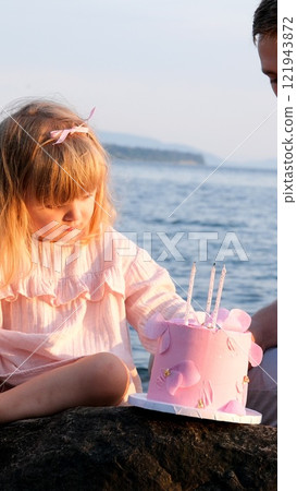 Birthday, parents and children with food by beach for event, celebration and party outdoors. Family, social gathering and mother, father with kids at picnic with cake, presents and eating together 121943872