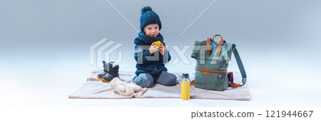 Little boy, dressed warm clothes, having rest, drinking warming drink, after interesting journey, against grey studio background. 121944667