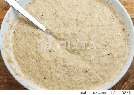Metal spoon in thick batter made with zucchini, rice flour and psyllium. Fresh plant-based dough 121945276