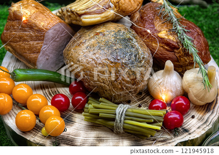Various hams and cured meats on platter surrounded by vegetables. Design butcher shop window display. Various hams and cured meats on platter surrounded by vegetables. Design butcher shop window display. 121945918