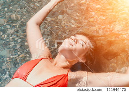Woman, Beach, Relaxation: A woman in a red bikini floats on her back in clear water on a sunny beach. Woman, Beach, Relaxation: A woman in a red bikini floats on her back in clear water on a sunny beach. 121946470