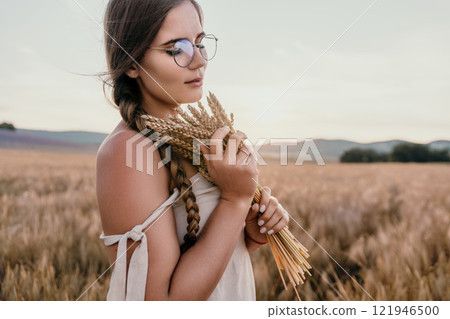 Young Woman in a Wheat Field Holding a Bunch of Wheat Young Woman in a Wheat Field Holding a Bunch of Wheat 121946500