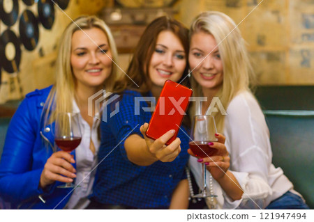 Girls in pub club taking self photo with phone Girls in pub club taking self photo with phone 121947494