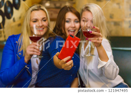 Girls in pub club taking self photo with phone Girls in pub club taking self photo with phone 121947495