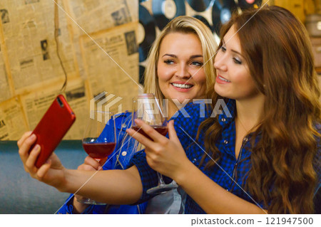 Girls in pub club taking self photo with phone 121947500