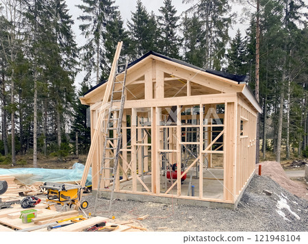 the process of building a frame house made of wood against a forest background 121948104