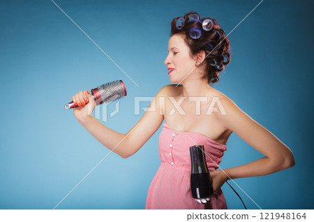 girl with curlers in hair holds hairdreyer girl with curlers in hair holds hairdreyer 121948164