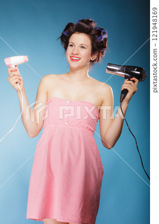 girl with curlers in hair holds hairdreyers girl with curlers in hair holds hairdreyers 121948169