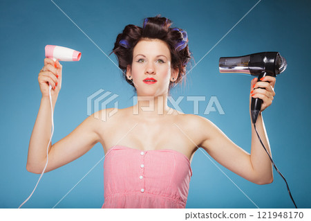 girl with curlers in hair holds hairdreyers 121948170