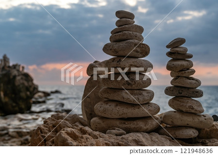 Rock Towers Beach Sunset - Two stone towers stacked on a beach with a sunset in the background. Rock Towers Beach Sunset - Two stone towers stacked on a beach with a sunset in the background. 121948636