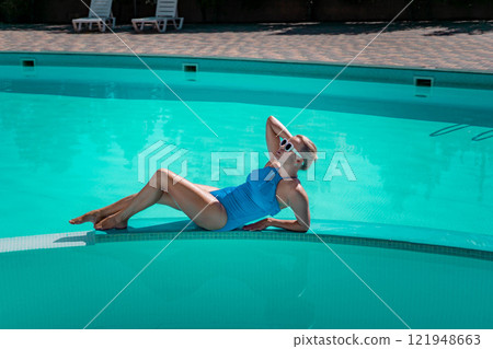 Bikini-clad woman enjoys poolside relaxation. Poolside ambiance. Capturing woman's relaxed time near pool. Bikini-clad woman enjoys poolside relaxation. Poolside ambiance. Capturing woman's relaxed time near pool. 121948663