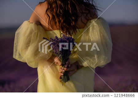 woman poses in lavender field at sunset. Happy woman in yellow dress holds lavender bouquet. Aromatherapy concept, lavender oil, photo session in lavender woman poses in lavender field at sunset. Happy woman in yellow dress holds lavender bouquet. Aromatherapy concept, lavender oil, photo session in lavender 121948666