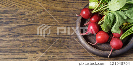 Radishes in wooden bowl on dark brown table Radishes in wooden bowl on dark brown table 121948704