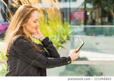 Girl using mobile phone on city street Girl using mobile phone on city street 121948883